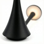 Close-up da luminária de mesa LED Elysium Touch, mostrando a emissão de luz quente e a textura do material preto fosco.