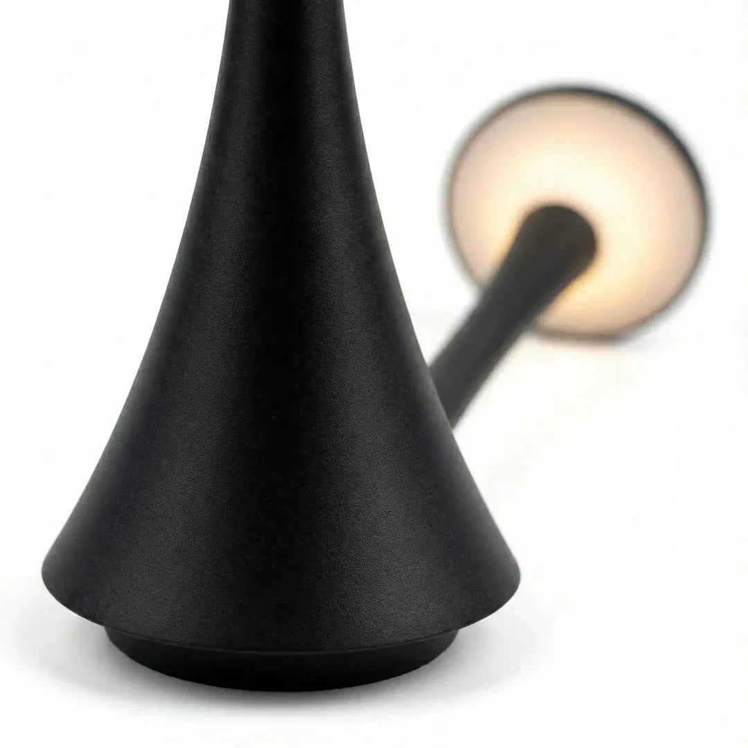 Close-up da luminária de mesa LED Elysium Touch, mostrando a emissão de luz quente e a textura do material preto fosco.