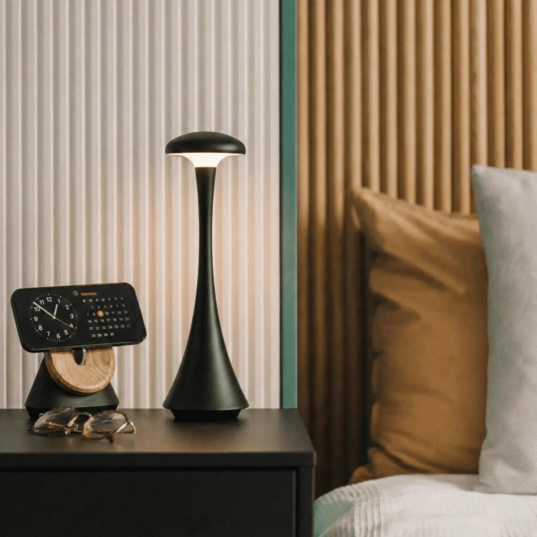 Luminária de mesa Elysium Touch Larvivaz acesa sobre um móvel de cabeceira, decorando um quarto moderno.