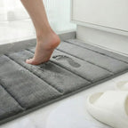 Demonstração de absorção e conforto do tapete para Larvivaz VelvetShield com pé descalço, destacando a maciez ao sair do banho.