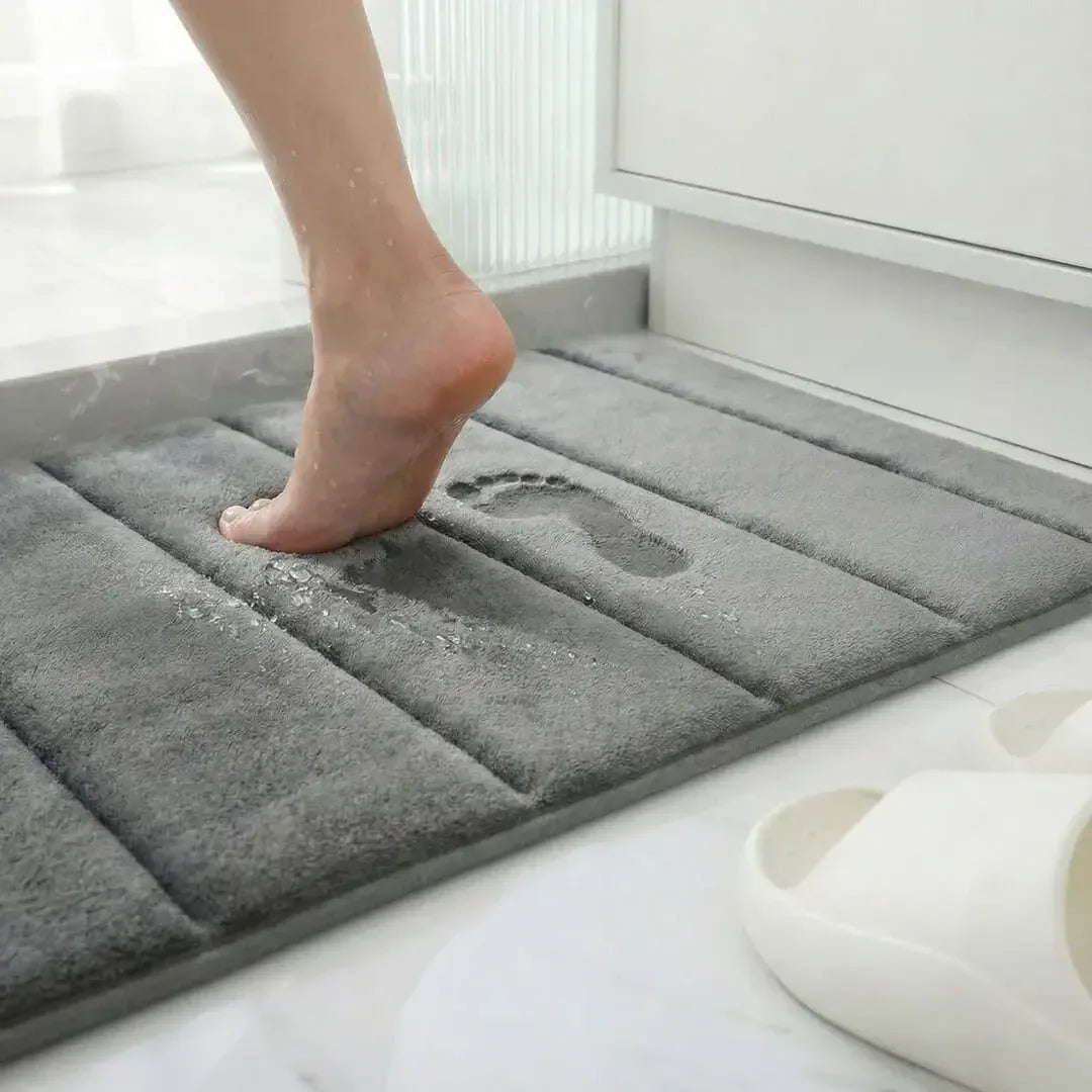 Demonstração de absorção e conforto do tapete para Larvivaz VelvetShield com pé descalço, destacando a maciez ao sair do banho.